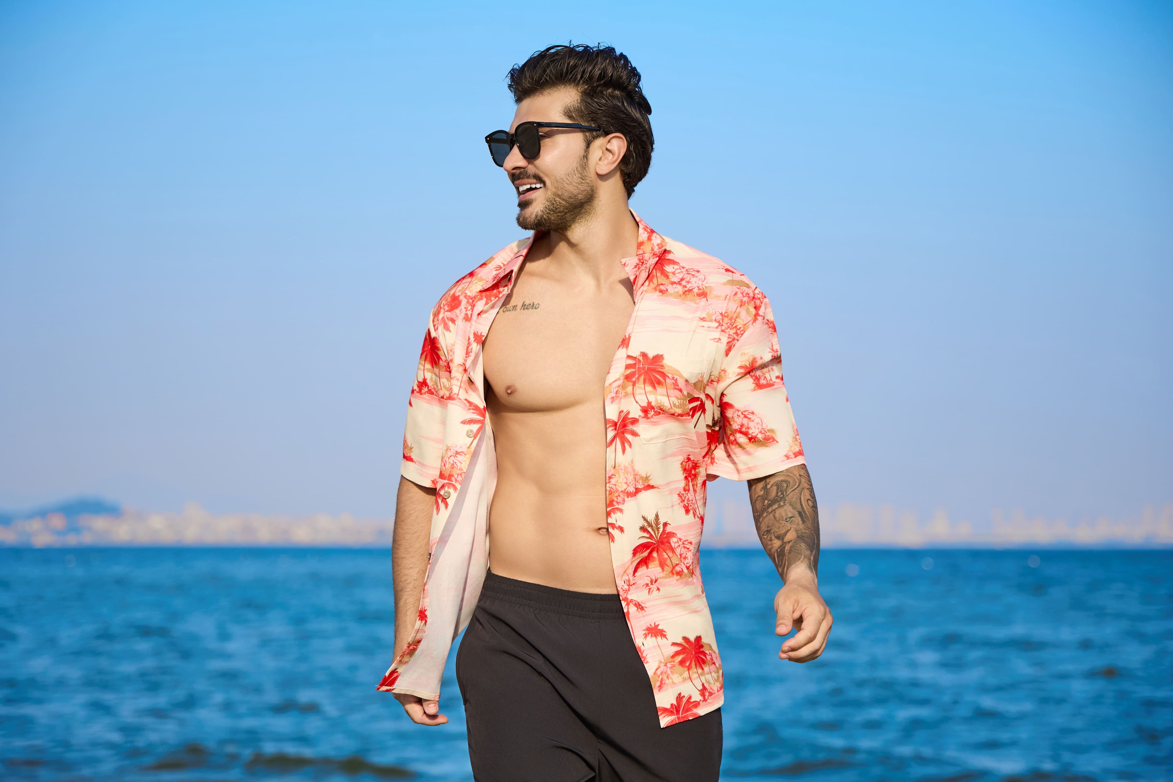 Man wearing a colorful shirt and sunglasses by the ocean