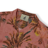 Pink tropical print shirt with palm leaves, brown buttons.