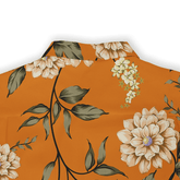 Orange floral shirt with beige flowers and green leaves on a solid.