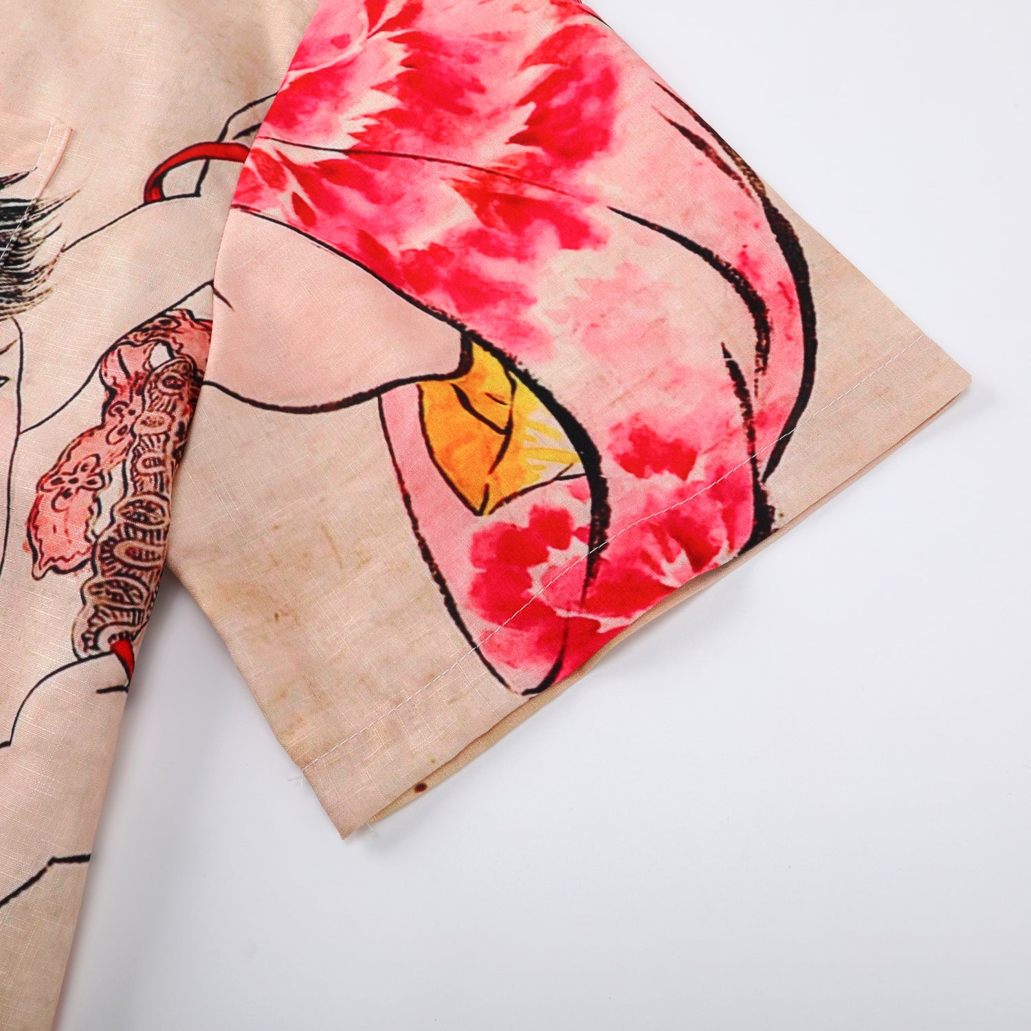 Beige fabric with red floral and yellow design, folded corner.