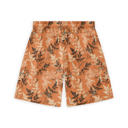 A pair of shorts featuring delicate black and light-colored fern patterns on an orange background, offering a nature-inspired design with an autumnal feel.