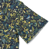 Forest-themed shirt with detailed plant and bird illustrations in green and blue tones.