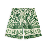 A pair of shorts featuring intricate green foliage, birds, and botanical patterns on a light background, creating a harmonious and nature-inspired design.