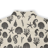 Seahorse and seashell print on a light-colored, ocean-inspired shirt.