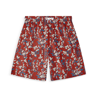 A pair of shorts featuring a floral design with delicate white blossoms and blue leaves set against a rich red background, creating a vibrant and harmonious pattern.