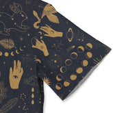 Close-up of a shirt sleeve featuring mystical gold designs on dark fabric, including hands, celestial symbols, and moon phases.