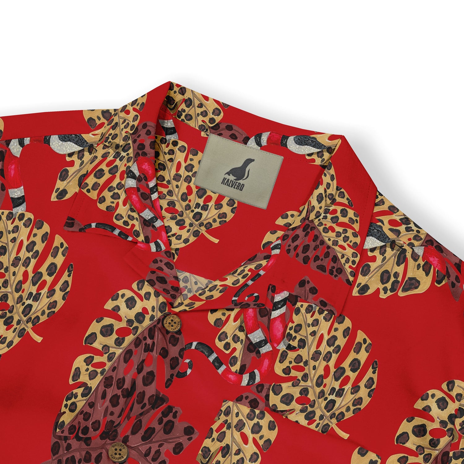 Close-up of a Hawaiian shirt collar with a bold red background, featuring large, multicolored leopard-print leaves and red accents. The Kalvero logo is visible on the inner tag.