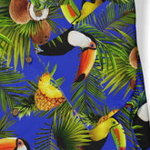 Close-up of a Hawaiian shirt, showcasing a vibrant pattern of toucans, pineapples, coconuts, and palm leaves against a bright blue background.