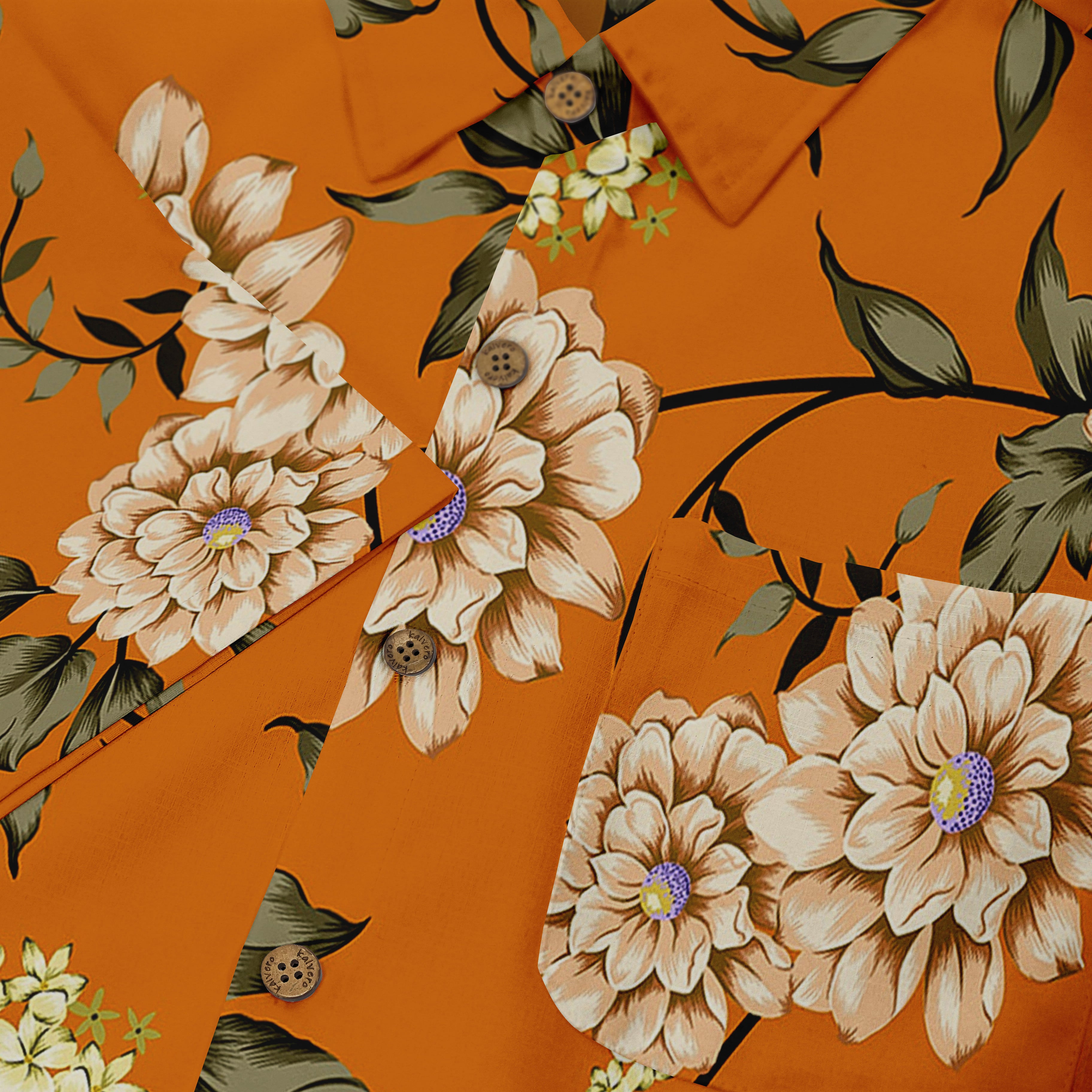 Close-up of a shirt with a floral design, featuring large beige and white flowers with green leaves on an orange background. The details highlight the intricate petals and delicate button accents, creating a bold yet elegant look.