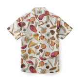 Short-sleeve shirt with a white background featuring a playful design of various mushrooms in earthy tones, including red, brown, and beige.