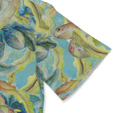 A close-up of the sleeve of a shirt featuring a detailed and colorful design with blue tropical flowers and sea turtles on a light blue background, showcasing the vibrant and lively print.