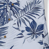 White shirt with blue tropical leaf print and wooden buttons.