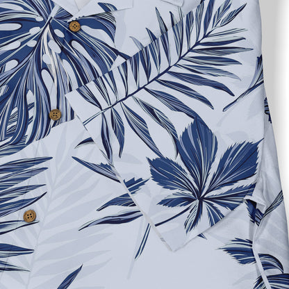 White shirt with blue tropical leaf print and wooden buttons.
