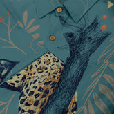 "Close-up of a shirt design featuring a leopard, tree branches, and leaves on a blue-green background with wooden-style buttons."