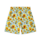 A pair of shorts featuring a vibrant design of large, bright yellow sunflowers and orange butterflies scattered across a light blue background, creating a cheerful and summery look.