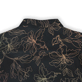 This image highlights the back of a dark shirt adorned with a fine, abstract floral pattern. The light, intricate lines of the flowers create a soft contrast against the dark background, giving the shirt a sophisticated and artistic appearance.