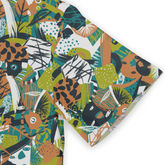 This is a close-up of a shirt sleeve featuring a vibrant abstract design in green, orange, black, and white. The pattern includes geometric shapes and leaves, contributing to a lively and bold style.