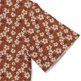 Brown fabric with white hibiscus flowers and geometric patterns.