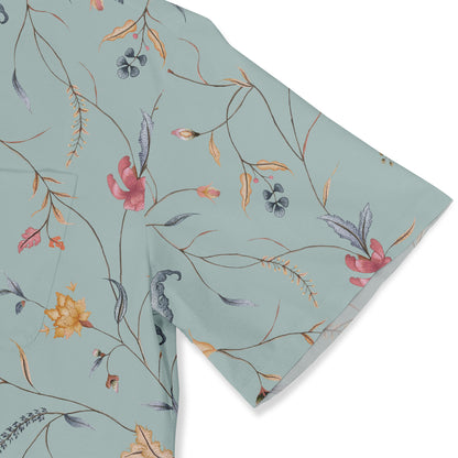 Close-up of a light green shirt sleeve with a delicate floral and botanical pattern, featuring thin branches and colorful flowers, adding a soft, elegant touch.