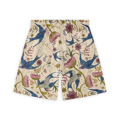 This is a close-up of the back of a pair of shorts featuring a whimsical design with vibrant blue birds and pink flowers, set against a light beige background. The pattern includes various floral elements and stars, giving the shorts a playful and artistic appearance.